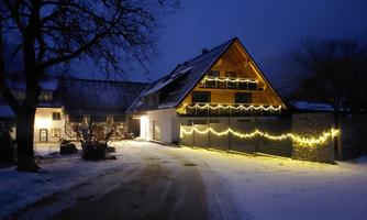 A beautifully lit house in winter at night. The path is covered with snow and the lights create a festive atmosphere.