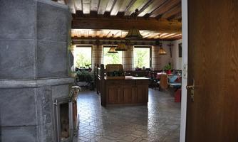 A cozy kitchen with wooden furniture and a large table. The windows let in plenty of daylight and the room feels inviting.