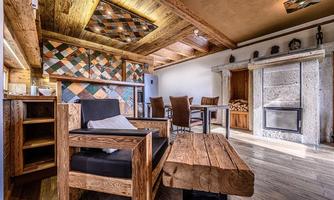 A modern living room with rustic wooden decor. There are cozy seating options and a fireplace in the room.
