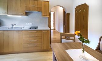 A cozy kitchen with wooden furniture and a small table decoration. The room feels bright and inviting.
