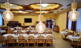 A cozy restaurant with elegant table decoration and wooden furniture. Modern lamps hang over the tables, creating a warm atmosphere.
