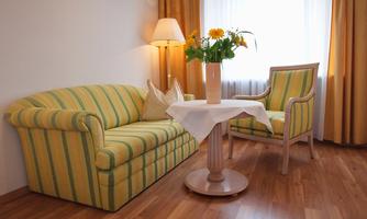 A cozy room with a striped sofa and an armchair. On the table, there is a vase with fresh flowers.
