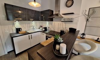 A modern kitchen with elegant black and white furniture. On the countertop, there are plants and kitchen utensils.