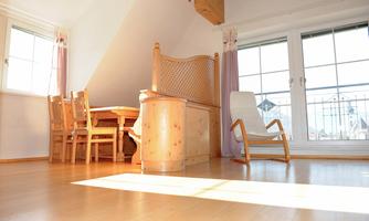 A cozy room with a wooden table and chairs. Large windows let in plenty of light and offer a view outside.