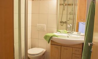 A modern bathroom with a shower, a sink, and a mirrored cabinet. The floor is decorated with a gray carpet and tiles.