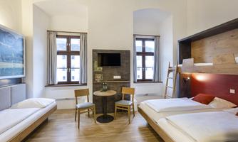 A modern room with two single beds and wooden flooring. Large windows provide plenty of daylight and a pleasant atmosphere.