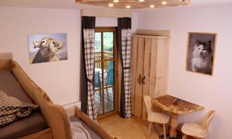A cozy room with wooden furniture and large windows. The walls are decorated with pictures of animals.