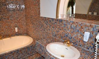 A stylish bathroom with a bathtub and a sink. The walls are decorated with colorful tiles.