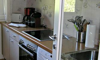 A modern kitchen with wooden shelves and a stove. In the background, various kitchen appliances and utensils are visible.