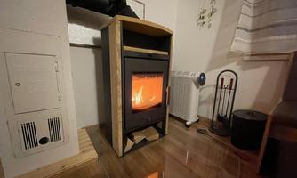 A modern stove stands in a cozy room and radiates warm light. Next to the stove, additional heating devices and decorative elements are visible.