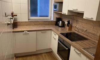 A modern kitchen with white cabinets and a wooden countertop. The kitchen features a stove, an oven, and a microwave.