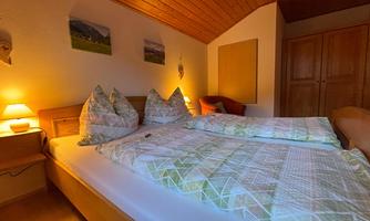 A cozy bedroom with a double bed and colorful cushions. Soft light from bedside lamps creates a relaxed atmosphere.