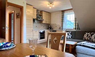 A bright, modern kitchen with a cozy living area. The table is set and the atmosphere is inviting.