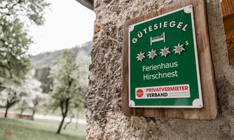 A sign with the quality seal for the holiday home Hirschnest. It displays three stars and information about the private landlord association.