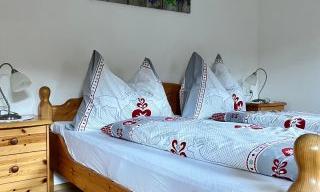 A cozy bedroom with a wooden bed and colorful bedspreads. Next to the bed are nightstands with lamps.