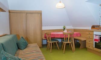 A cozy living kitchen in the attic with a seating area and a dining table. The room is bright and invitingly designed.