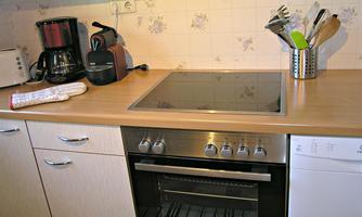 A modern kitchen with a stove and various kitchen appliances. The workspace is tidy and well-organized.