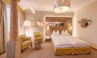 An elegant hotel room with a large bed and stylish furniture. Soft colors and a cozy atmosphere make the space inviting.