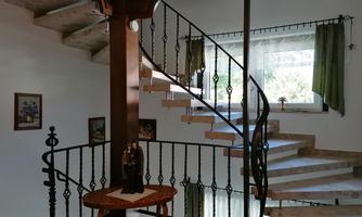 An inviting staircase area with a curved stairway and a decorative railing. Bright walls and windows create a friendly atmosphere.