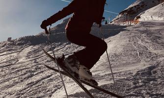 A person is skiing on a snow-covered slope. The sky is clear and blue.