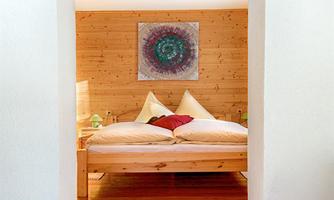 A cozy bedroom with a large bed and wood-paneled walls. There is a decorative picture on the wall and soft light from the bedside lamps.