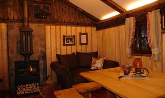 A cozy wooden room with a sofa and a dining table. A fireplace creates a warm atmosphere.