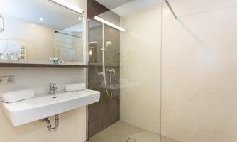 A modern bathroom with a glass shower and a simple sink. The walls are bright and the lighting creates a pleasant atmosphere.