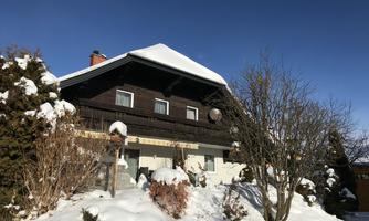 A picturesque, snow-safe house with a white roof and a conservatory. Surrounding it is a quiet, snow-covered landscape.