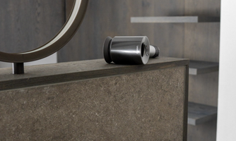 A modern bathroom with an elegant sink faucet and a mirror. In the background, wooden shelves are visible, giving the room a stylish ambiance.