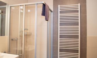 A modern bathroom with a glass shower and a towel holder. The walls are brightly tiled, creating a pleasant atmosphere.