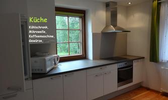 A modern kitchen with white cabinets and a kitchen unit. It is equipped with a refrigerator, a microwave, and a stove.