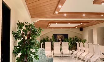 A relaxing interior with loungers and plants. The ceiling is clad in wood and the lighting is soft.