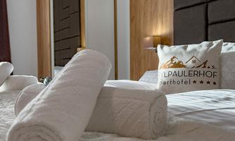 A stylish bedroom with a large bed and fresh towels. A mirror and wooden elements give the room a cozy atmosphere.