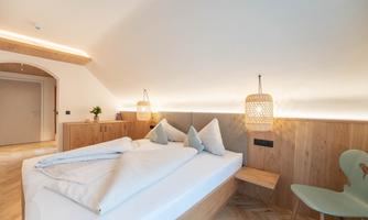 A cozy bedroom with a large bed and modern wood design. The room has a warm atmosphere with soft lighting and stylish furniture.