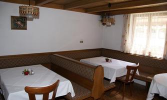 A cozy restaurant with wood paneling and round tables. The tables are covered with white tablecloths and decorated.