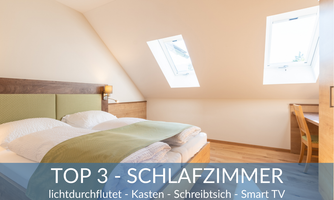 A bright bedroom with a double bed, wooden floor, and a desk. Large skylights provide plenty of natural light.