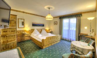 A cozy room with wooden furniture and a double bed. Large windows provide plenty of daylight and a pleasant atmosphere.
