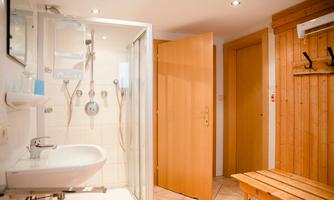 A modern bathroom with a shower and a sink. Wood paneling and a bright atmosphere create an inviting environment.