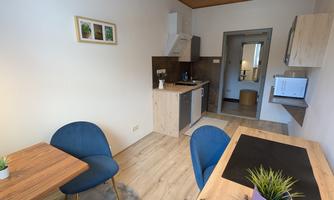 A modern kitchen unit with a table and blue chairs. The room has a bright atmosphere and is well equipped.