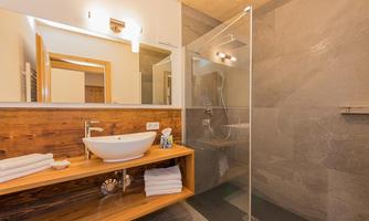 A modern bathroom with a glass shower and an elegant sink. Wood and stone elements give the room a warm atmosphere.