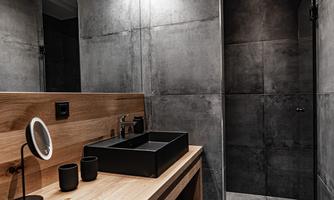 A modern bathroom with gray walls and a wooden washbasin. The lighting is soft and accentuated, creating an elegant atmosphere.