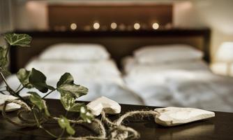 A cozy bedroom with two beds and soft lighting. Decorative hearts and plants create a relaxed atmosphere.