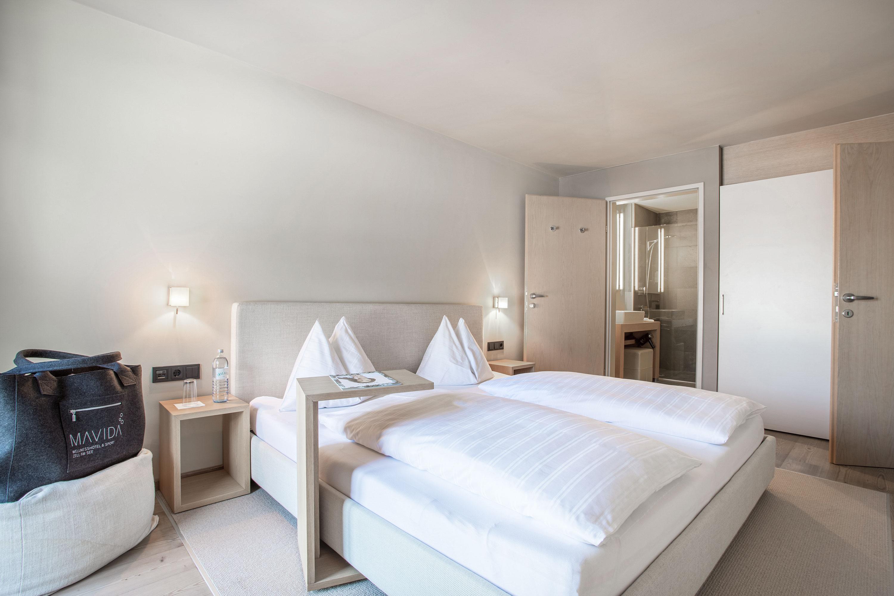 A modern bedroom with a double bed and two nightstands. The walls are bright, and the room feels inviting and tidy.