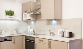 A modern kitchen with bright cabinets and an elegant countertop. It is well-equipped and includes various appliances such as a stove and a microwave.