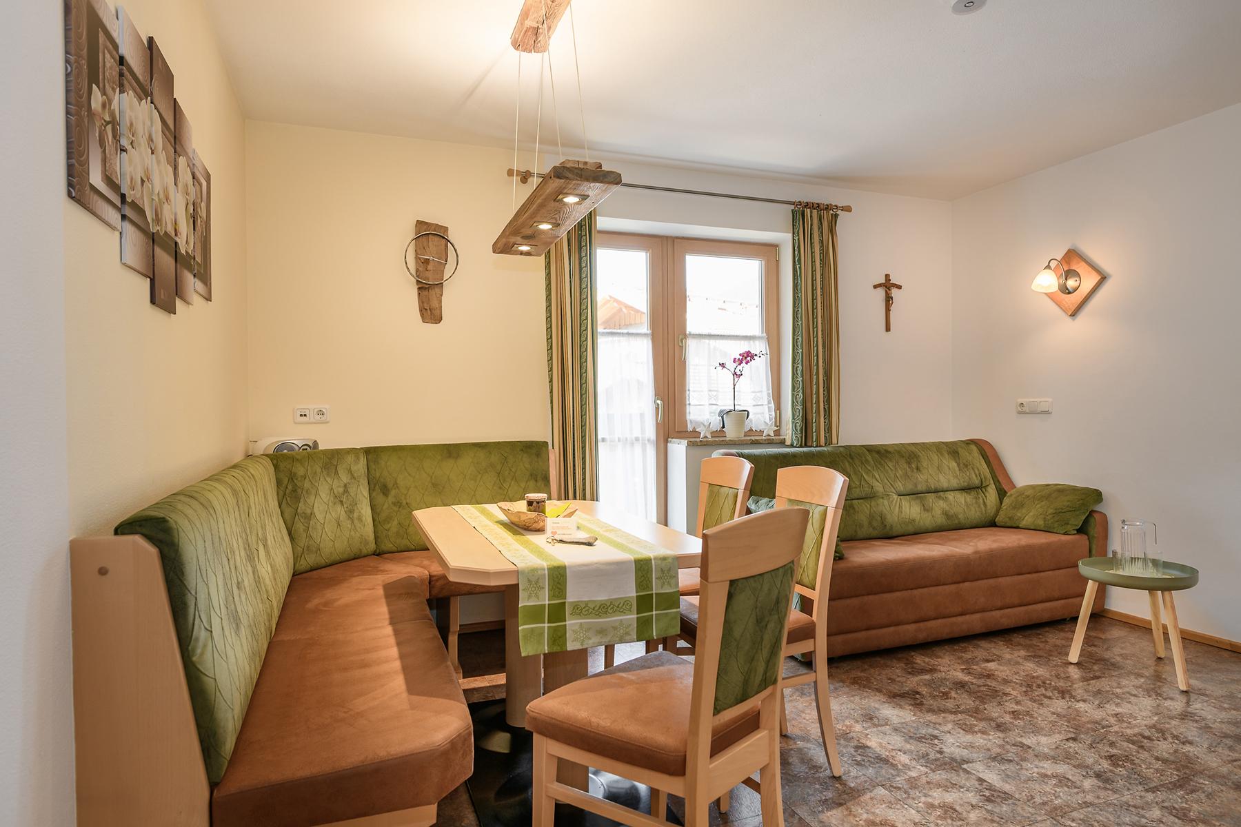 A cozy room with a table and a seating area. The green cushions give the atmosphere an inviting touch. The kitchenette is well equipped and features a stove with oven, refrigerator with freezer compartment, microwave, kettle, toaster, and ample dishes. The mountain lifts, ski lifts, and the swimming pool with sauna are just a few meters away.