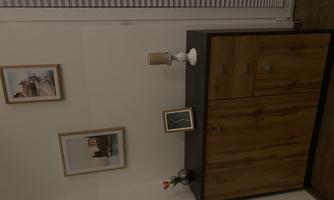 A wooden sideboard with closed compartments stands against the wall. On it are decorations like picture frames, a candle, and a small plant.