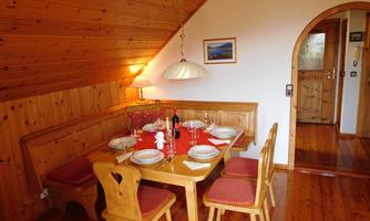 A cozy dining area with a wooden-clad roof. A table is set for a feast with dishes and wine.