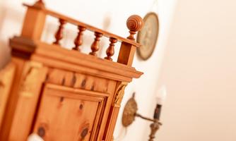 A beautiful, handcrafted wooden bed with decorative details. In the background, wall lamps and a clock are visible.