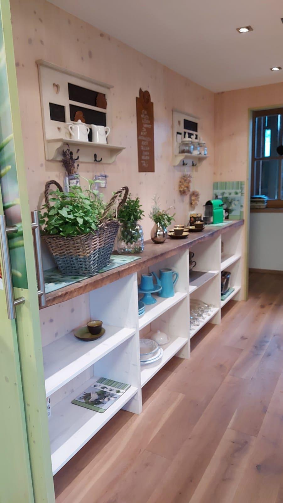A stylish kitchen with a wooden shelf and decorative plants. Various kitchen utensils and dishes can be seen on the shelves.
