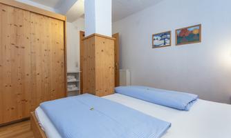 A cozy bedroom with wooden cabinets and two single beds. Colorful pictures hang on the wall.